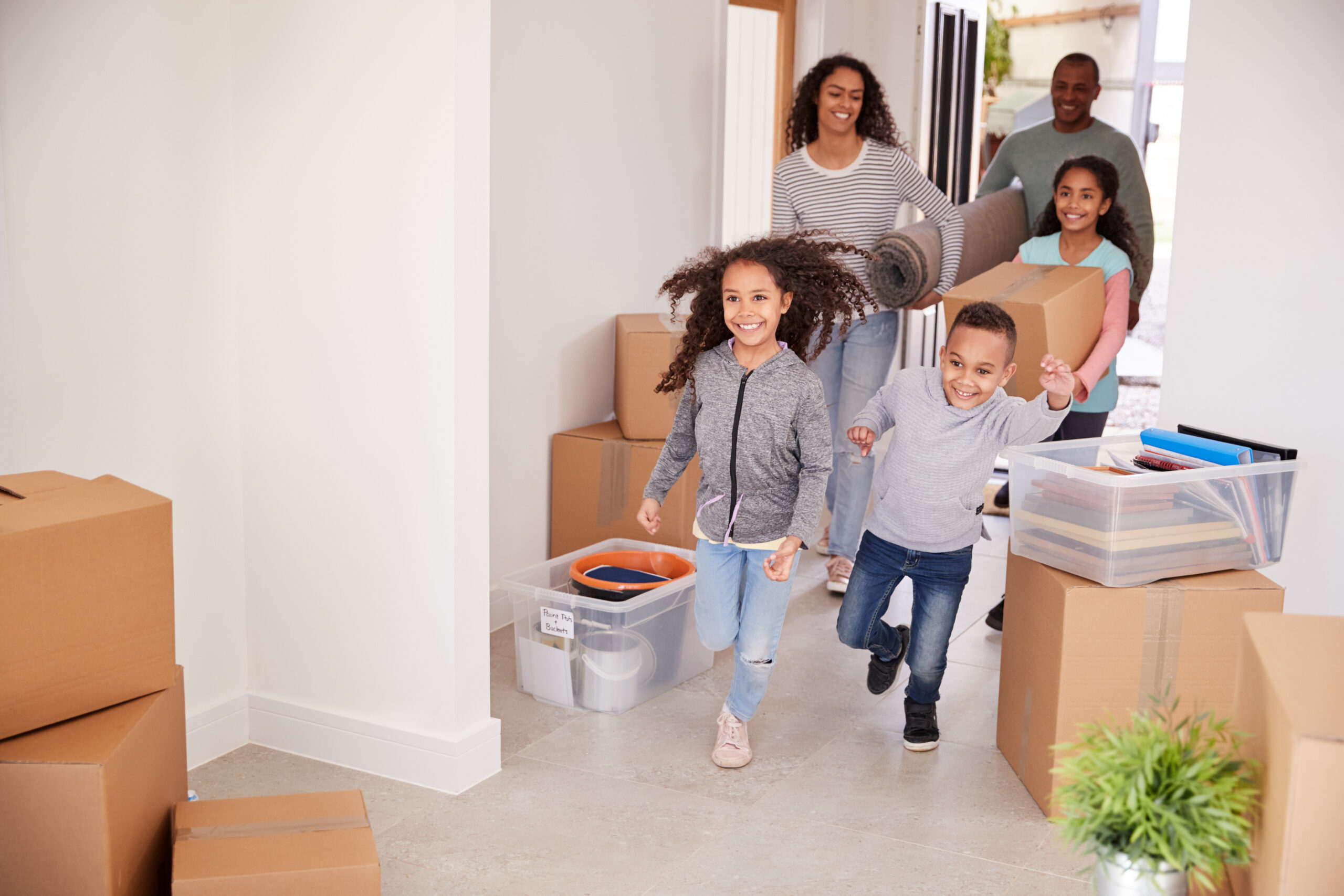 Smiling Family Carrying Boxes Into New Home